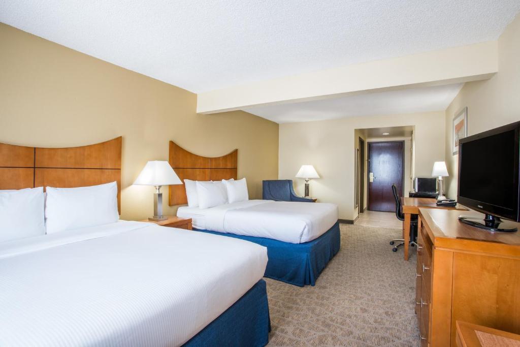 a hotel room with two beds and a flat screen tv at Wingate by Wyndham - Universal Studios and Convention Center in Orlando