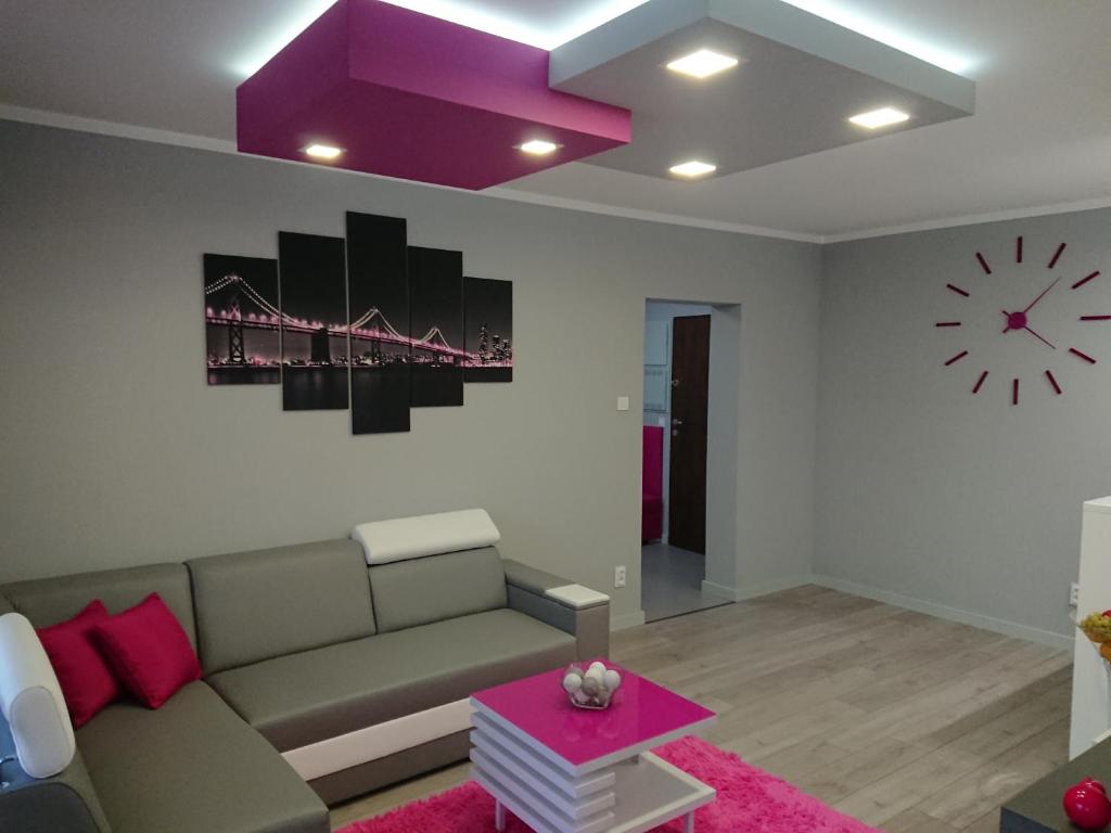 salon z kanapą i zegarem na ścianie w obiekcie Apartament Exclusive w Kielcach