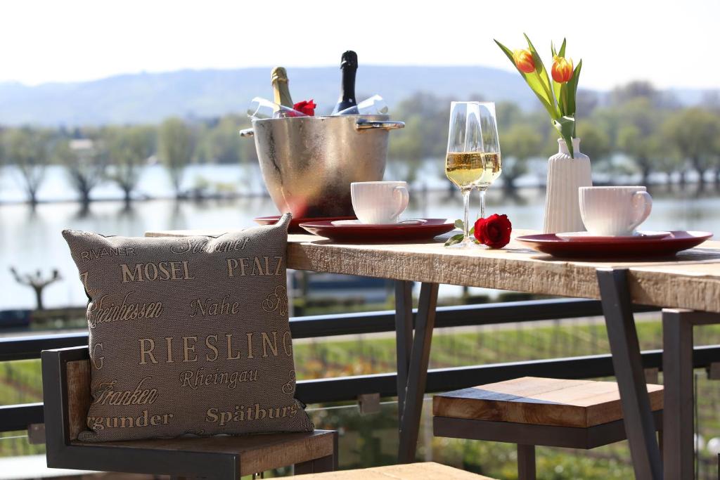 a table with a glass of wine and a table with a view of the water at Nägler´s Fine Lounge Hotel in Oestrich-Winkel