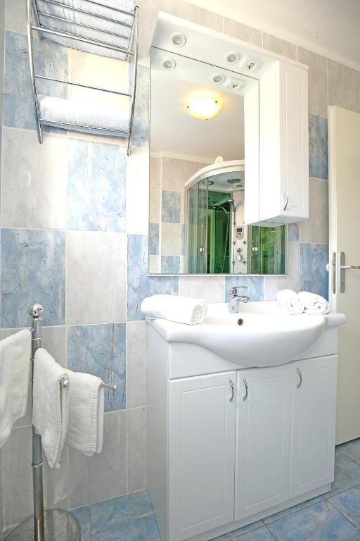 łazienka z białą umywalką i lustrem w obiekcie Apartments SOLARIS - with PRIVATE PARKING w mieście Sveti Filip i Jakov