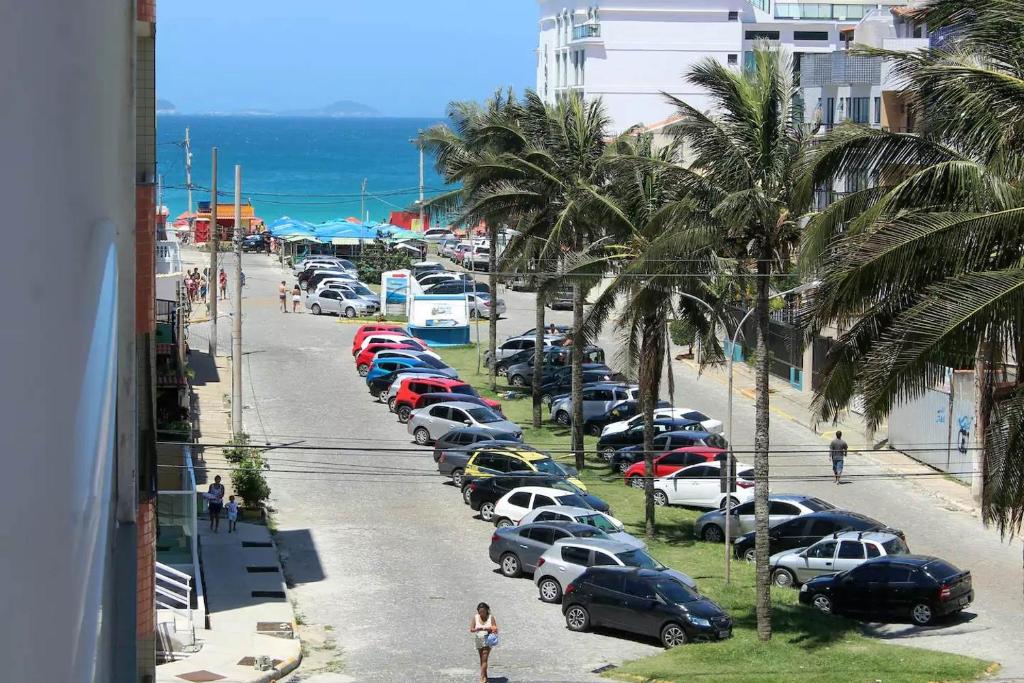 Una fila de autos estacionados en una calle al lado de la playa en Aconchego no Paraíso, en Arraial do Cabo