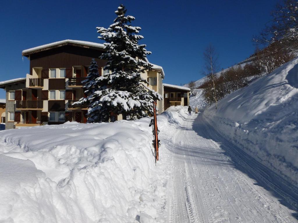 a snow covered road in front of a building with a tree at Hotel Jam Session in Les Deux Alpes
