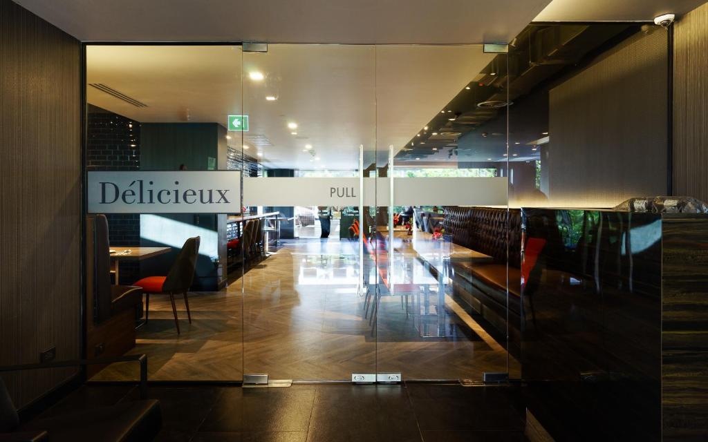 A glass-fronted hotel entrance opening onto a polished dining or lounge area.