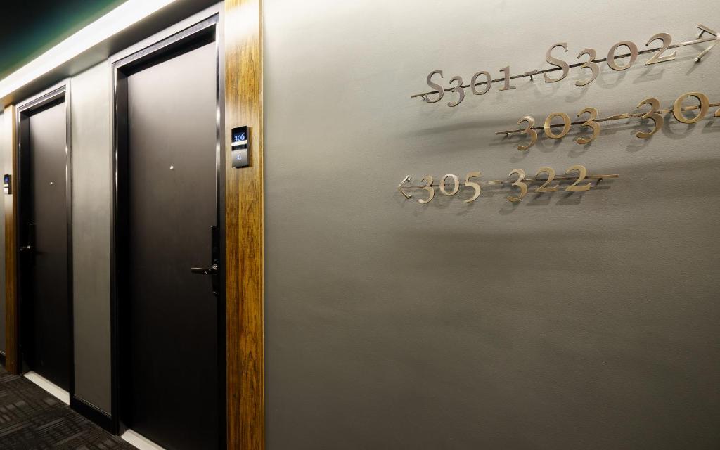 A hallway with elevator doors and wall-mounted room-direction signage.