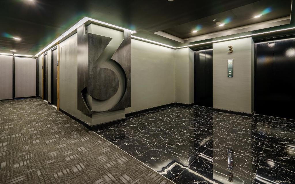 A broad elevator lobby with a large sculptural number 3 and multiple lift doors.