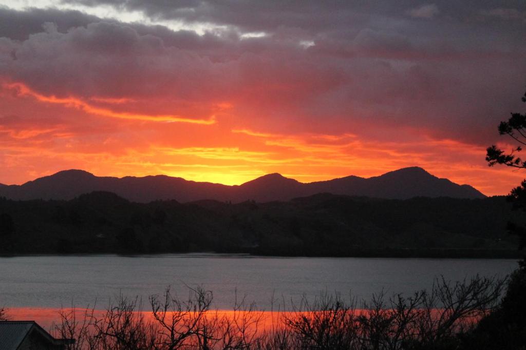 a sunset over a lake with mountains in the background at Brockies B n B in Rawene