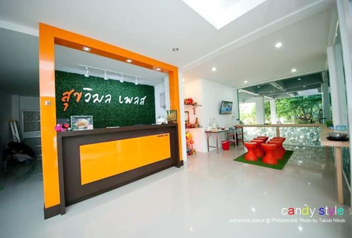 sala de estar con pared amarilla y naranja en Sukwimol Place, en Phitsanulok