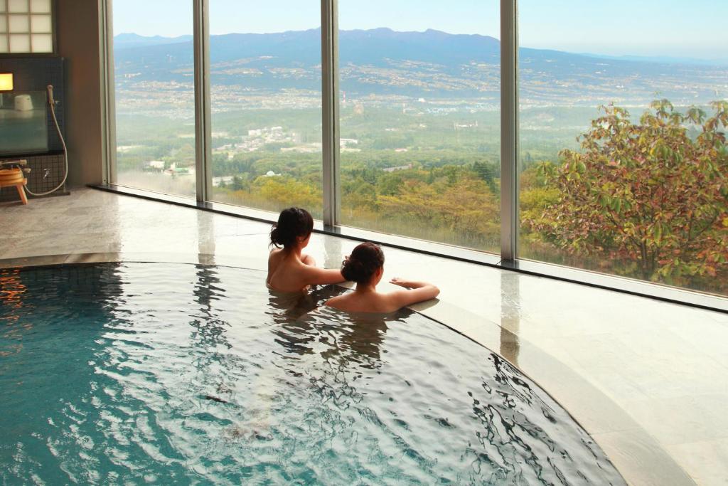 two people sitting in a swimming pool in a building at Shinki in Shibukawa