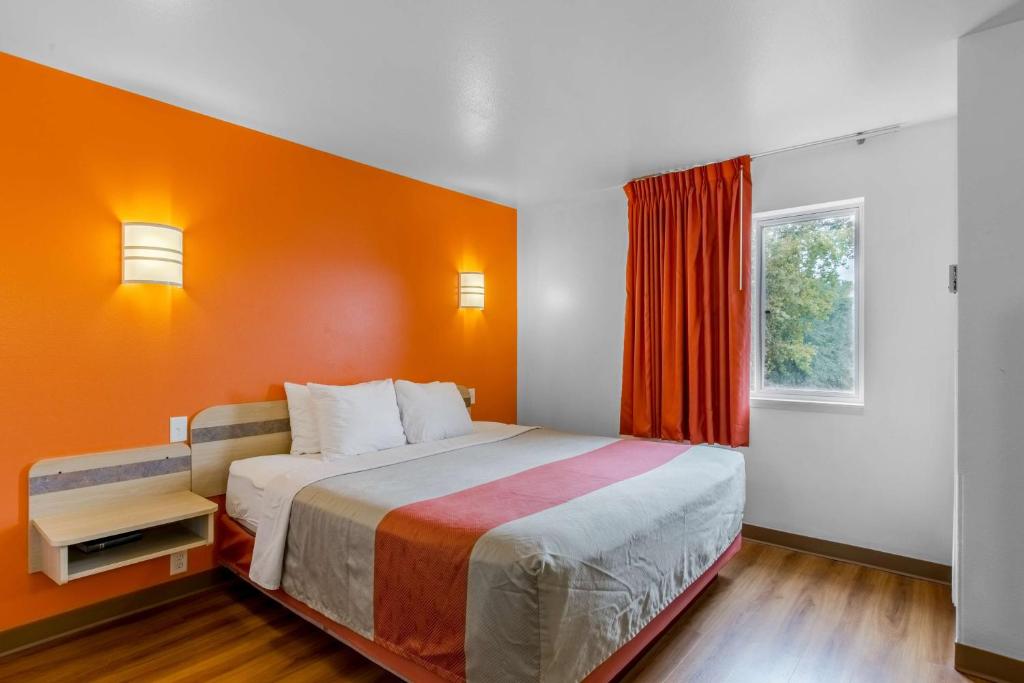 Un dormitorio con una cama grande con una pared naranja. en Motel 6-Baraboo, WI - Lake Delton-Wisconsin Dells, en Baraboo