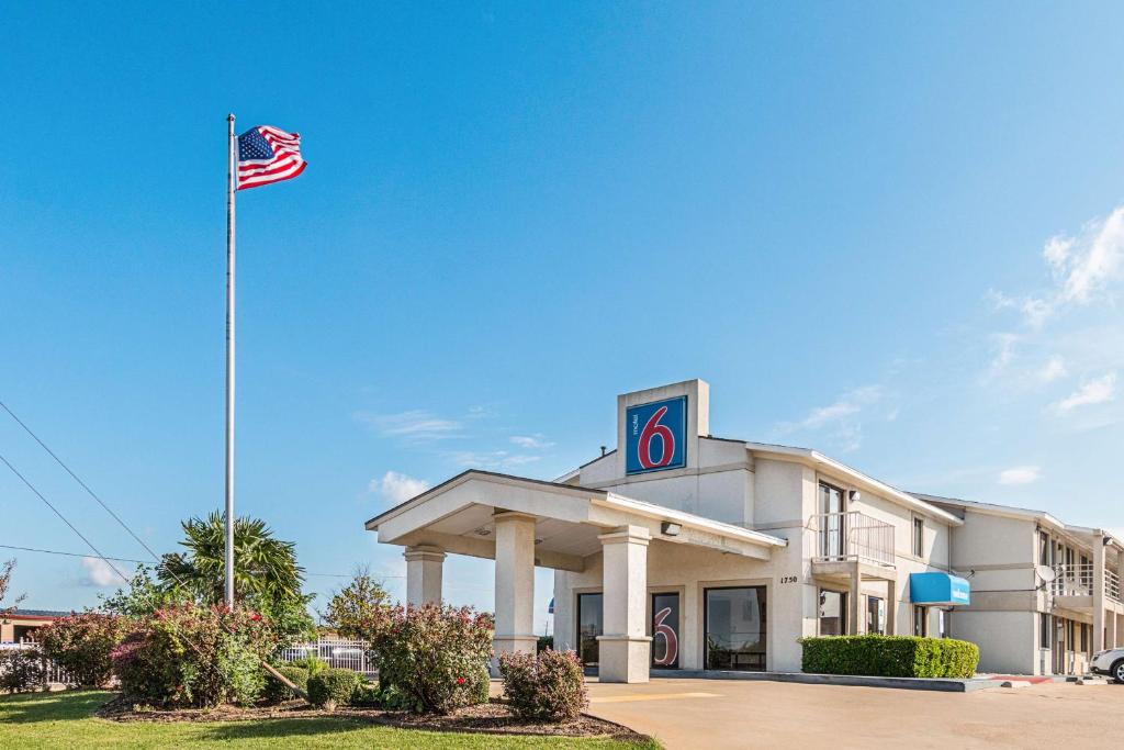 un edificio con una bandera americana delante de él en Motel 6-Lancaster, TX - DeSoto - Lancaster, en Lancaster