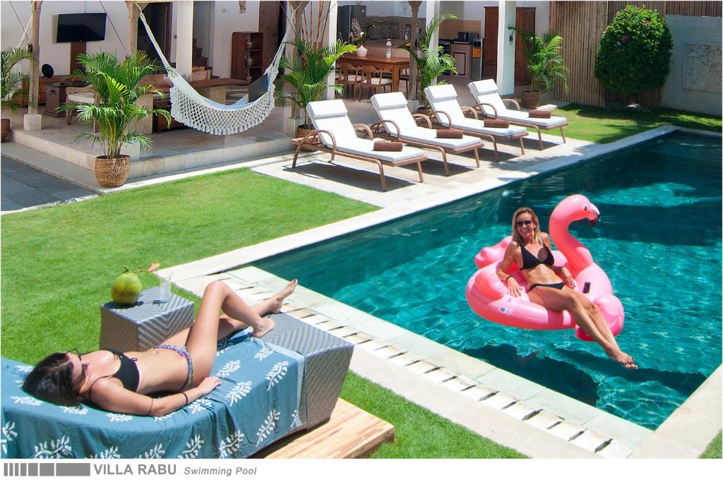 Dos mujeres están nadando en una piscina con un flamenco en 3BR Villa Rabu - Minggu Villas Seminyak, en Seminyak