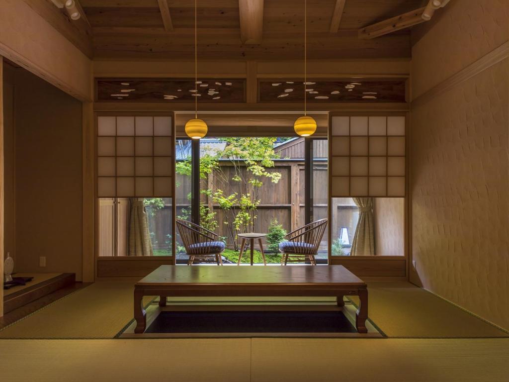 een kamer met een tafel, 2 stoelen en ramen bij Yunotani Senkei in Totsukawa