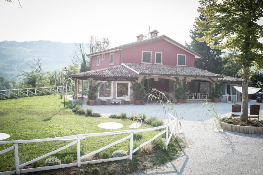 ein rosafarbenes Haus mit einem weißen Zaun davor in der Unterkunft Agricola casa cucina bottega in Cesena
