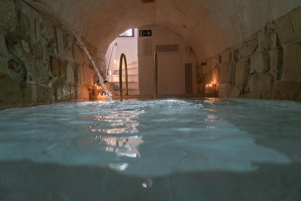 una piscina de agua en un edificio con un túnel en S'Hotelet d'es Born - Suites & SPA, en Ciutadella