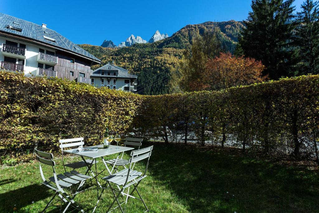 une table et des chaises assises sur l'herbe dans une cour dans l'établissement Apartment Triolet Jardin - Garden with Mont Blanc Views, à Chamonix-Mont-Blanc