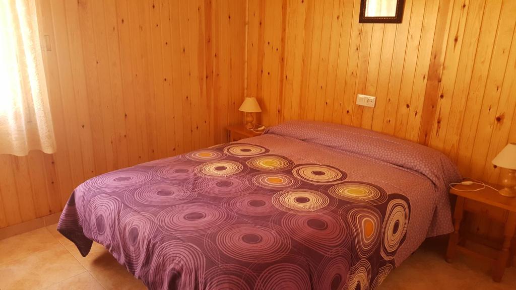 ein Schlafzimmer mit einem lila Bett in einem Holzzimmer in der Unterkunft Casa Joan in Barruera