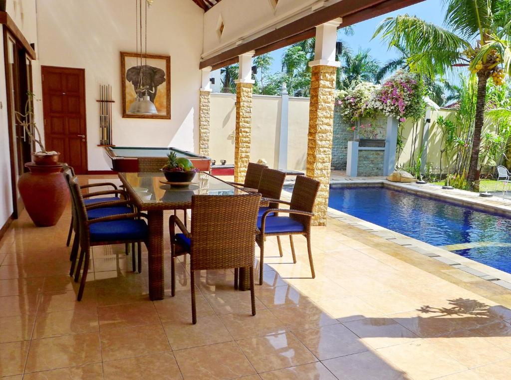 a dining room with a table and chairs and a swimming pool at Villa Stella Garden in Senggigi