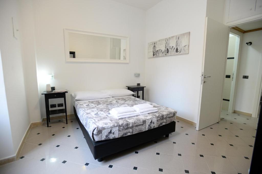 a white bedroom with a bed and two tables at Casa Andrew in Rome