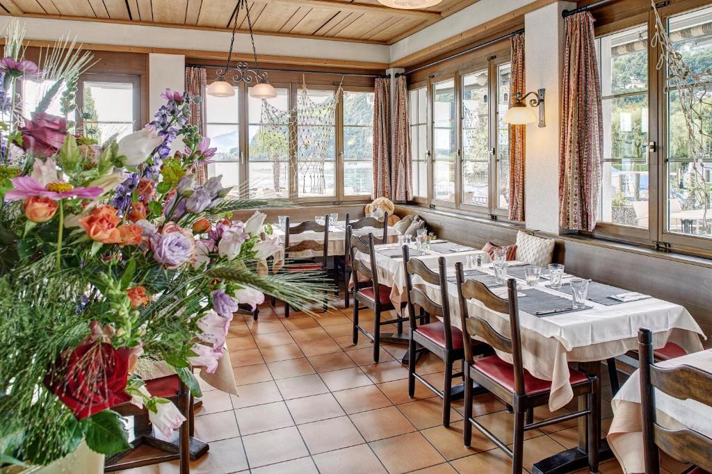 a restaurant with tables and chairs in a room with windows at Hotel Winkelried am See in Stansstad