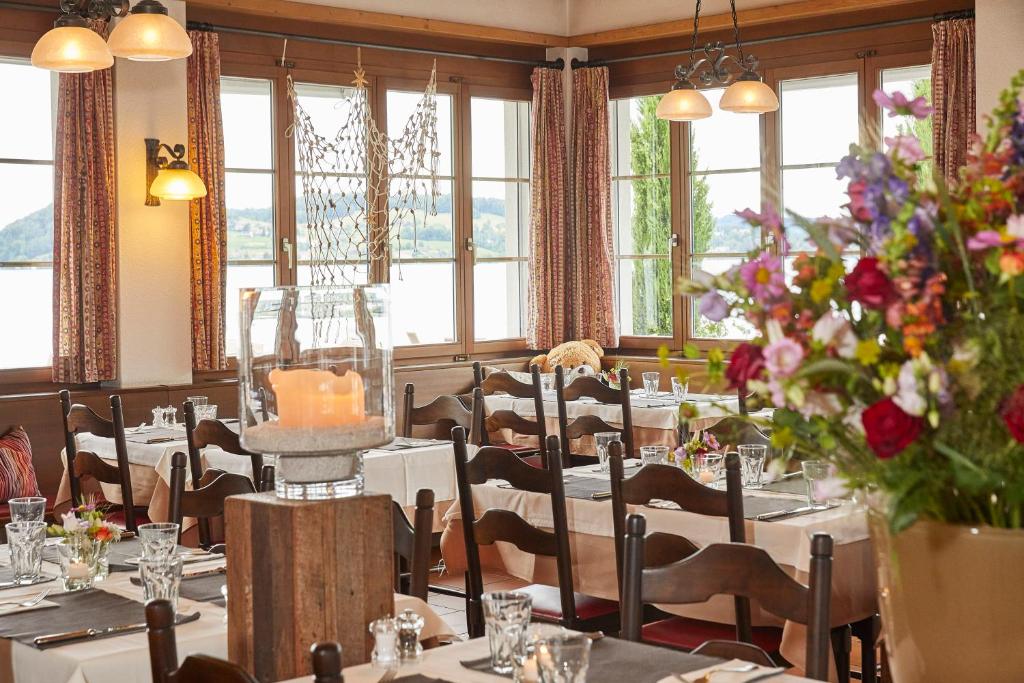 a dining room with tables and chairs and flowers at Hotel Winkelried am See in Stansstad