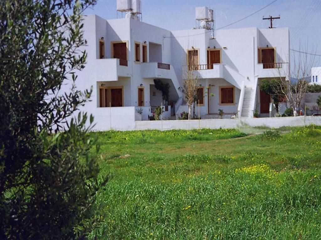 a white building with a grass field in front of it at Pela Apartments in Sisi