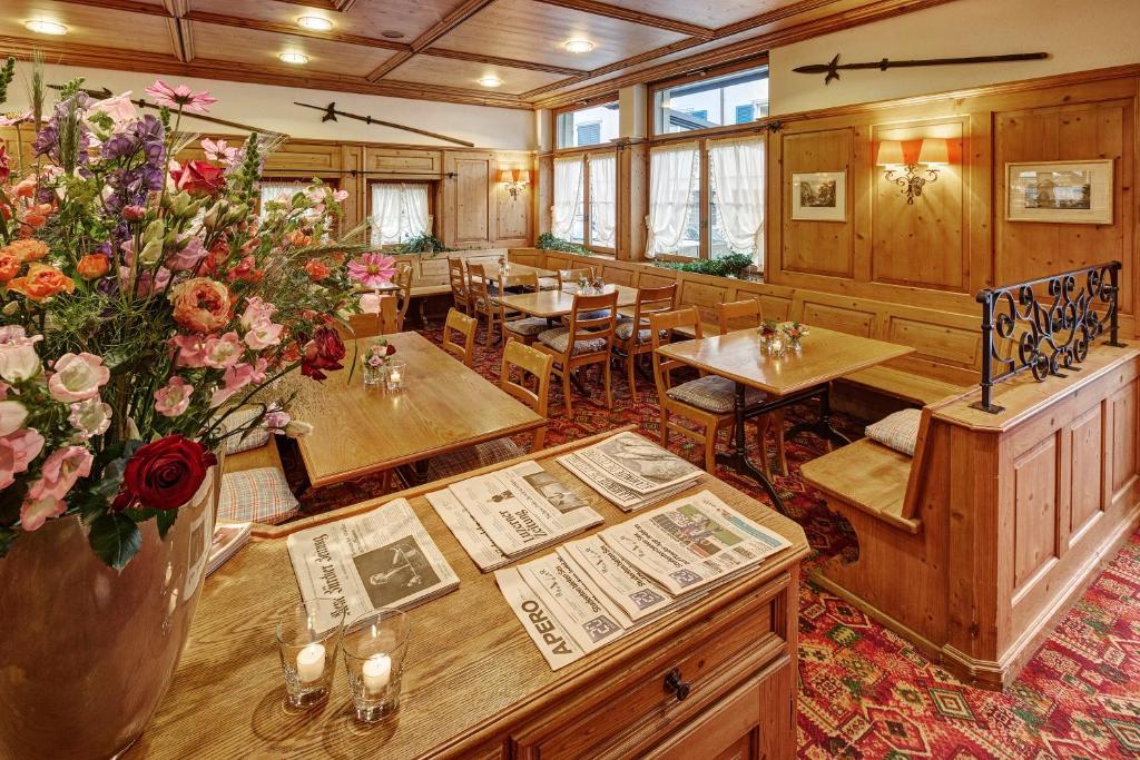 a restaurant with tables and chairs and a vase of flowers at Hotel Winkelried am See in Stansstad