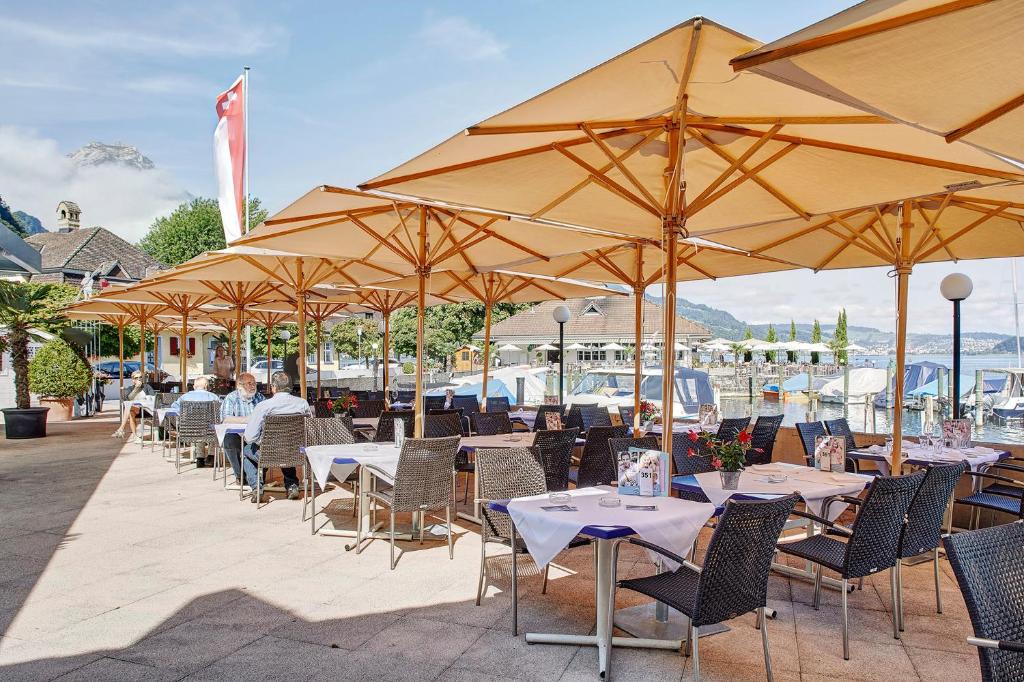 a row of tables and chairs with umbrellas at Hotel Winkelried am See in Stansstad