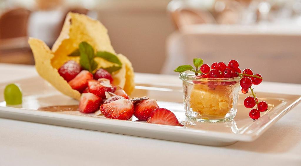 a plate of fruit with berries and a jar of honey at Hotel Winkelried am See in Stansstad