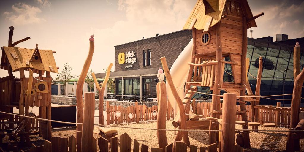 a playground with wooden play equipment in front of a building at bäck stage in Mössingen