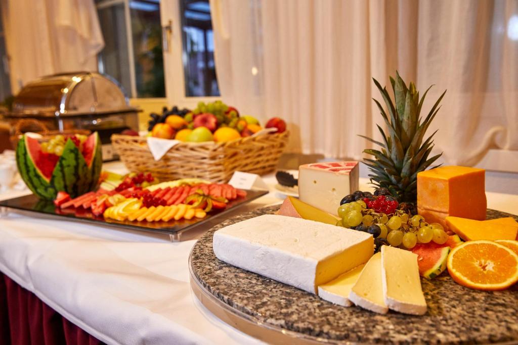 a table with cheese and fruit on a table at Hotel Winkelried am See in Stansstad
