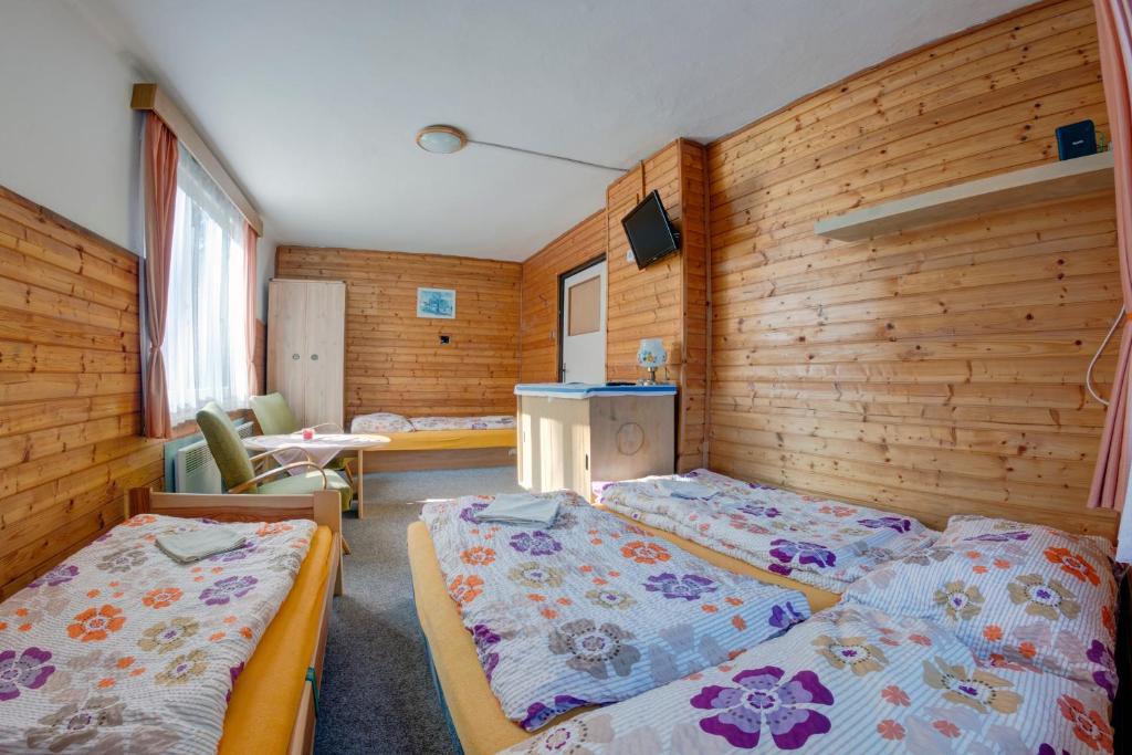 Habitación con 2 camas en una habitación con paredes de madera. en Chata Špindlerův Mlýn 256, en Špindlerův Mlýn
