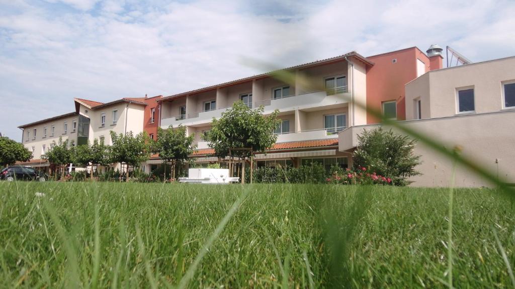 a row of apartment buildings in a field of grass at Hotel Le Chatard in Sarcey