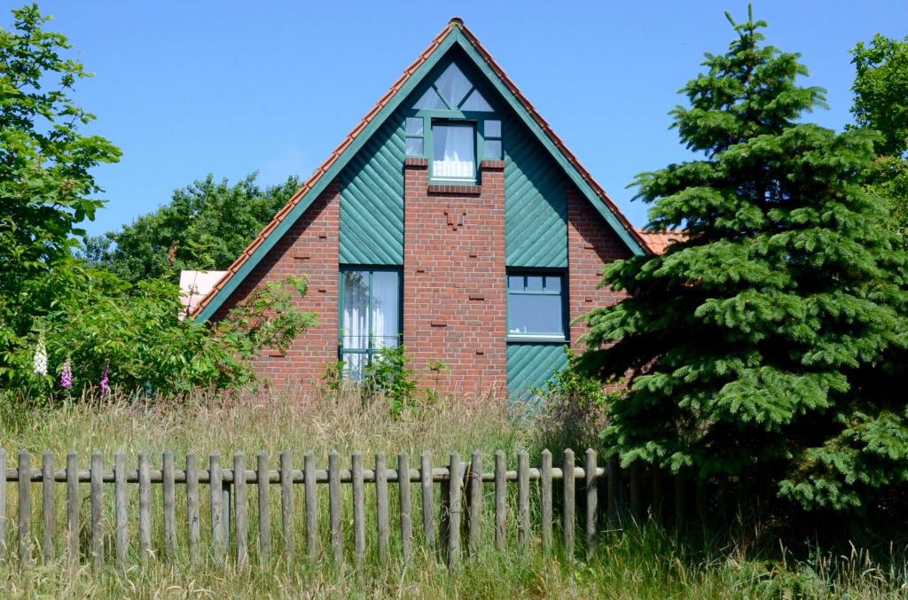 ein grünes Haus mit einem Zaun davor in der Unterkunft FH Austernfischer I/Nr. 1 in Spiekeroog