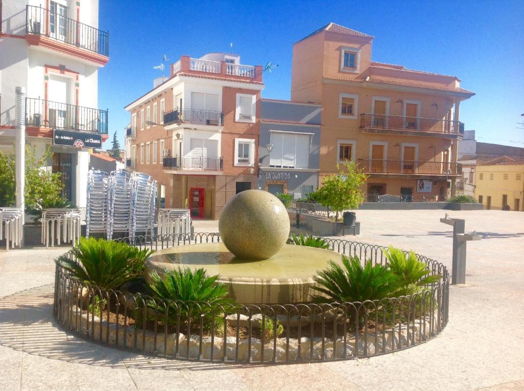 a sculpture in the middle of a courtyard with buildings at A.T. La Plaza in Calamonte