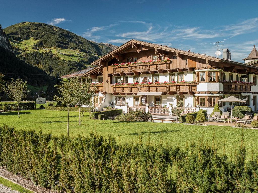 a large building with a green field and mountains at Appartementhaus Sonnenschein in Mayrhofen