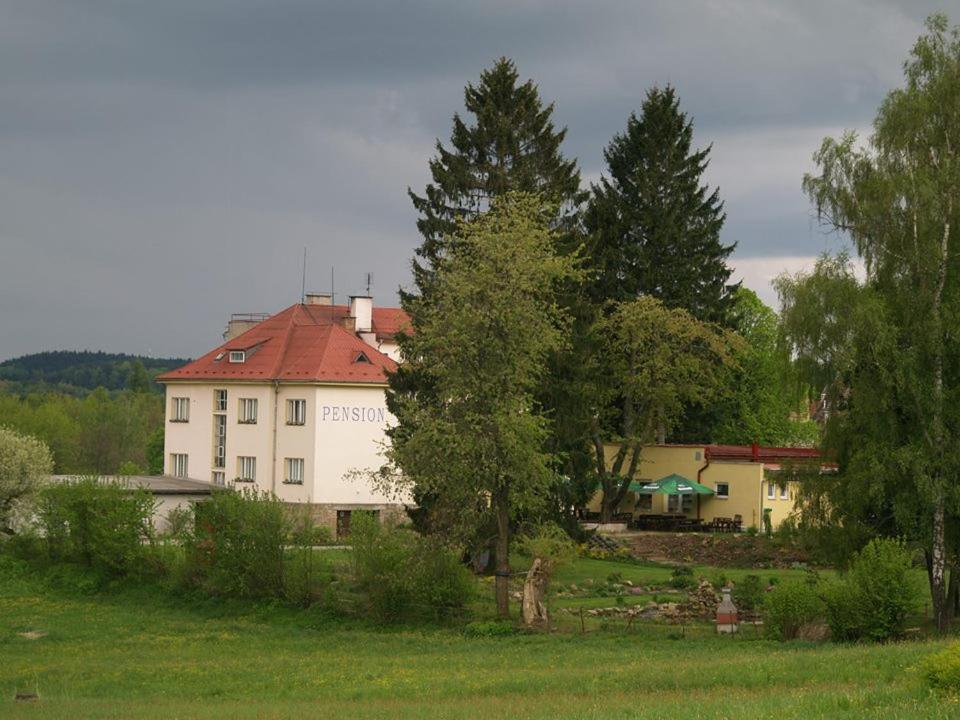 una grande casa bianca con tetto rosso e alberi di Pension Pod Šibeňákem a Strmilov
