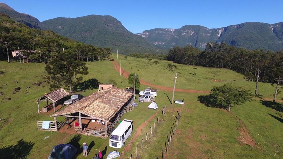 a group of people standing around a house in a field at Pousada Recanto Da Fortaleza in Pedra