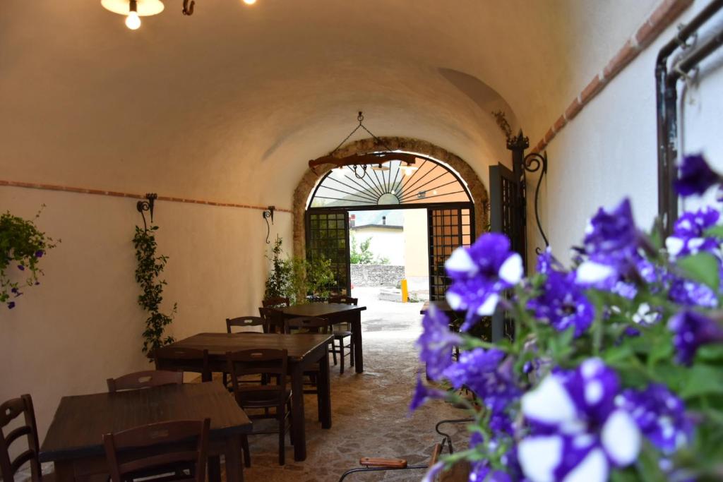 un restaurante con mesas de madera y flores púrpuras en Locanda Corte Dè Guasconi en Avezzano