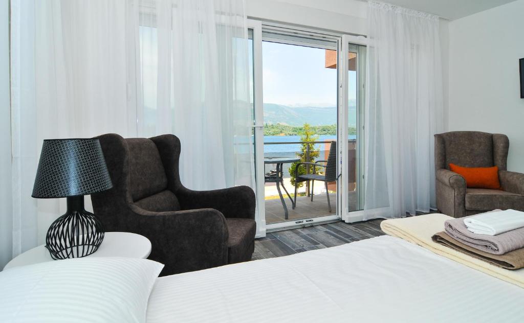 a bedroom with a bed and two chairs and a balcony at Apartments Edera in Tivat