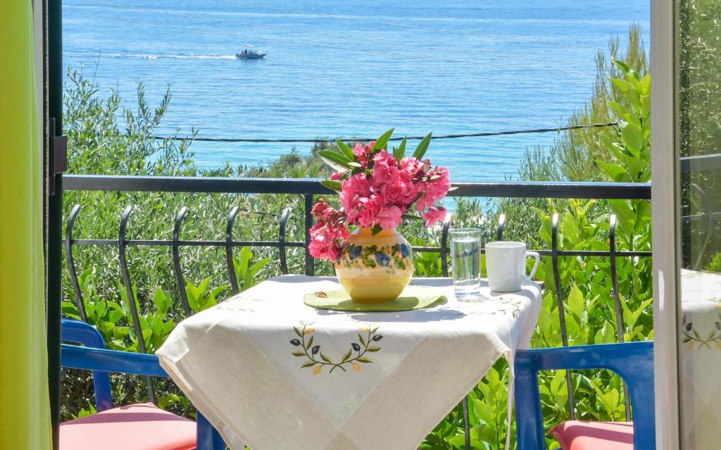 una mesa con un jarrón de flores en el balcón en Alex-Giannis Apartments, Barbati, en Barbati