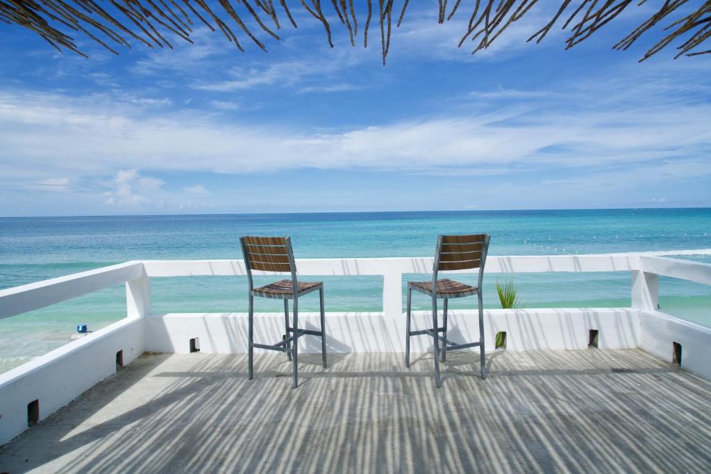 two chairs sitting on a balcony looking at the ocean at White Sands Negril in Negril