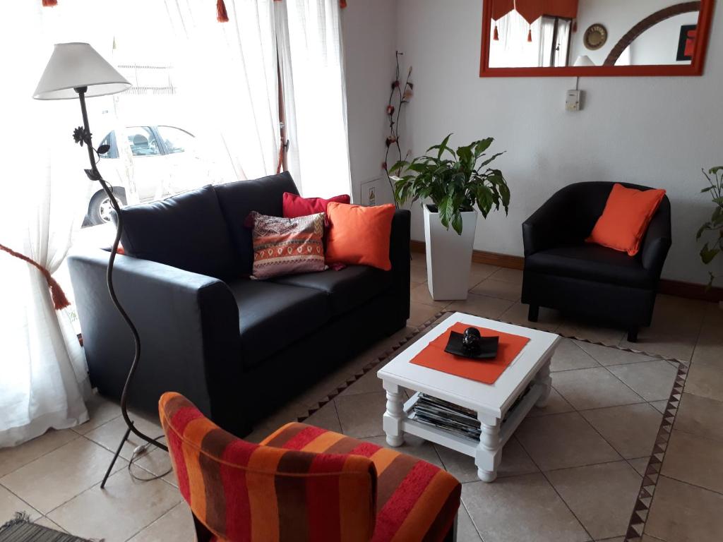 a living room with a black couch and a table at Hotel Aldea Marina in Villa Gesell