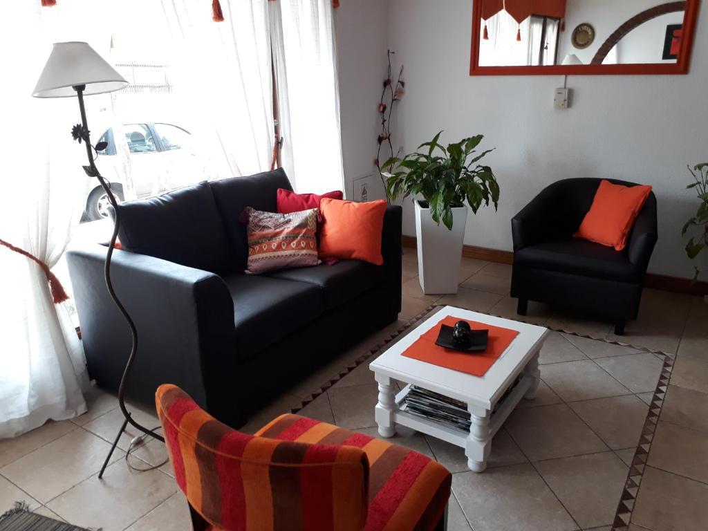 Una sala de estar con un sofá negro y una mesa. en Hotel Aldea Marina, en Villa Gesell