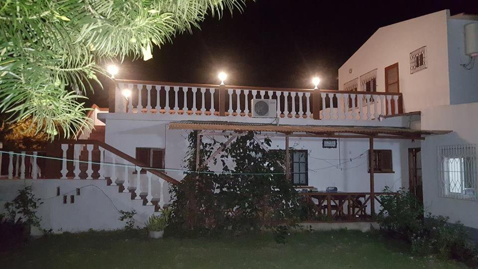 uma casa branca com uma varanda à noite em VIP House-Praia Francesca em São Tomé