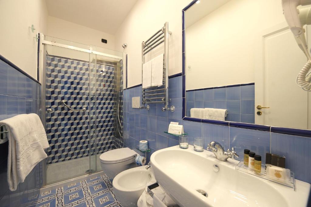 a blue and white bathroom with a sink and a toilet at Hotel Aurora in Amalfi