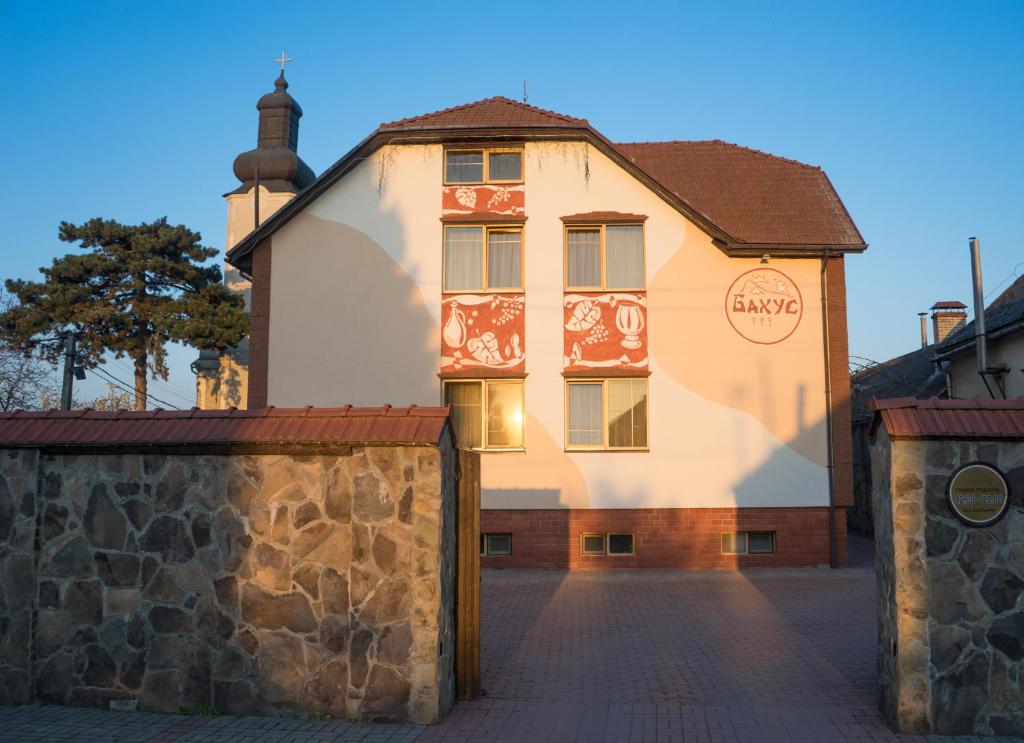 a large white building with a stone wall in front of it at Hotel Complex Bahus in Uzhhorod