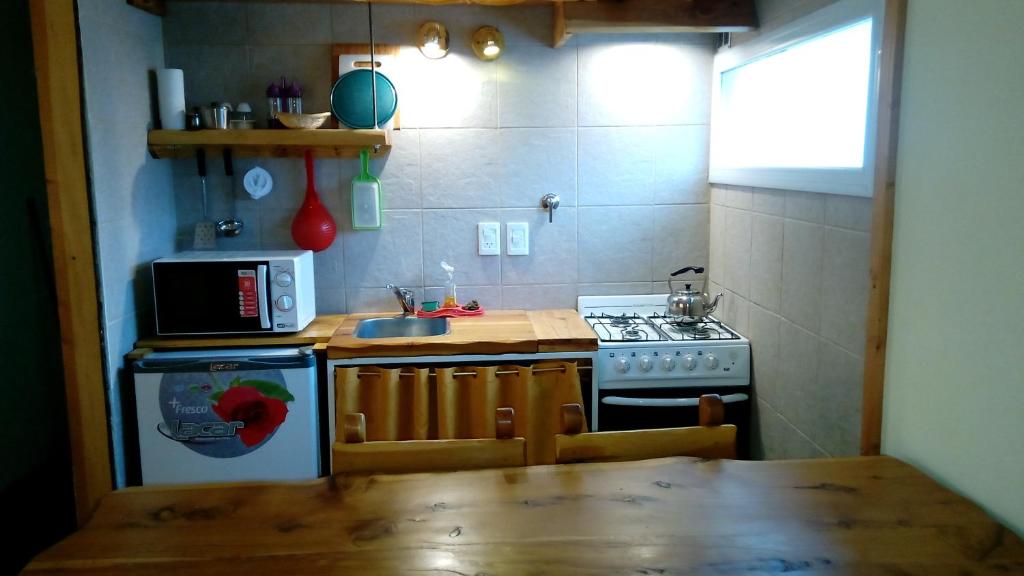 a kitchen with a table and a stove and a sink at Departamentos de Alquiler Turistico: Familia Eguren in San Carlos de Bariloche