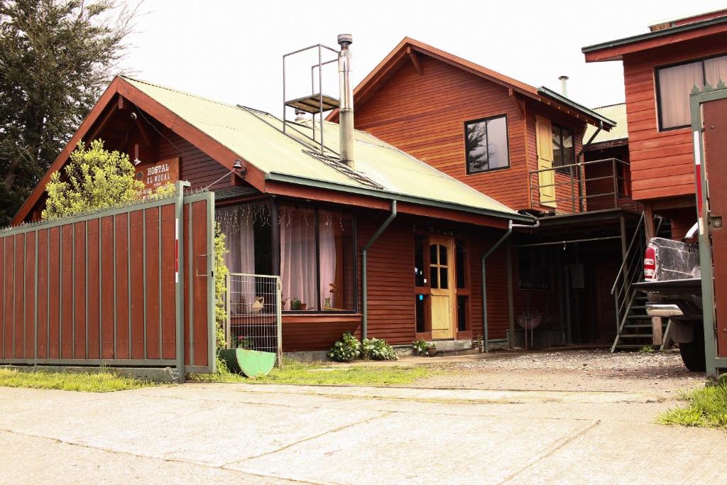 uma casa de madeira com uma cerca em frente em Hostal el Nogal Pucón em Pucón