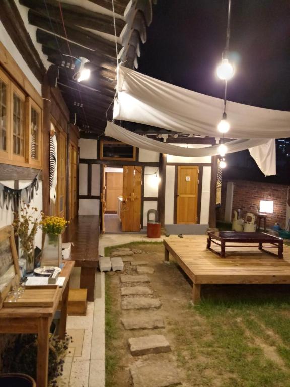a patio with wooden tables and a white tent at Hundred Years Hanok in Mokpo