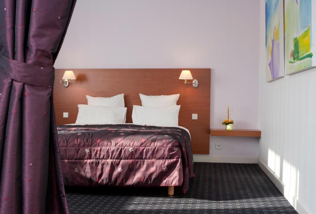 Habitación de hotel con cama con almohadas blancas en Hôtel Restaurant Logis La Palette, en Wettolsheim